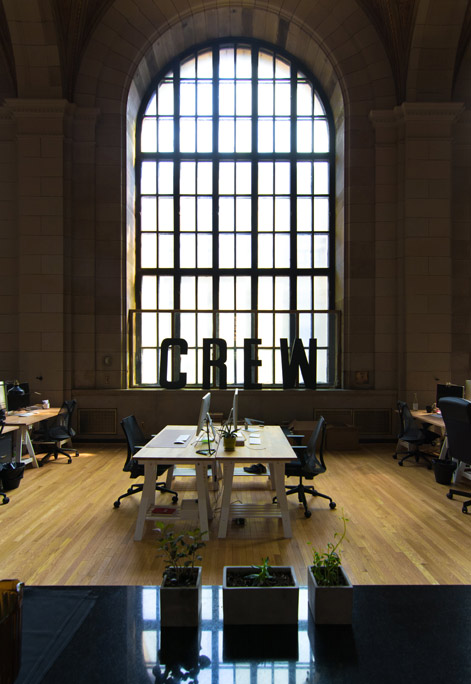 Blick in ein Büro mit großem Fenster und Arbeitsplätzen.